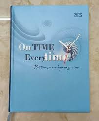 Blue notebook with a clock on a wooden surface