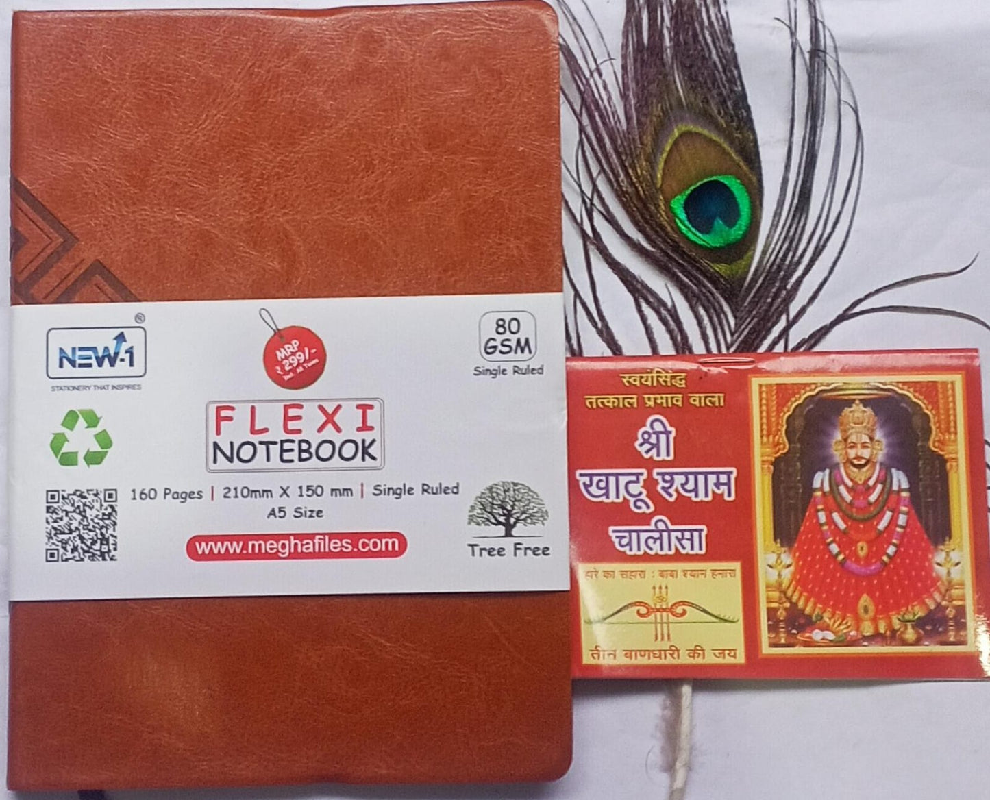 Brown flexi notebook with a peacock feather and a small card featuring an image of a deity on a white background.