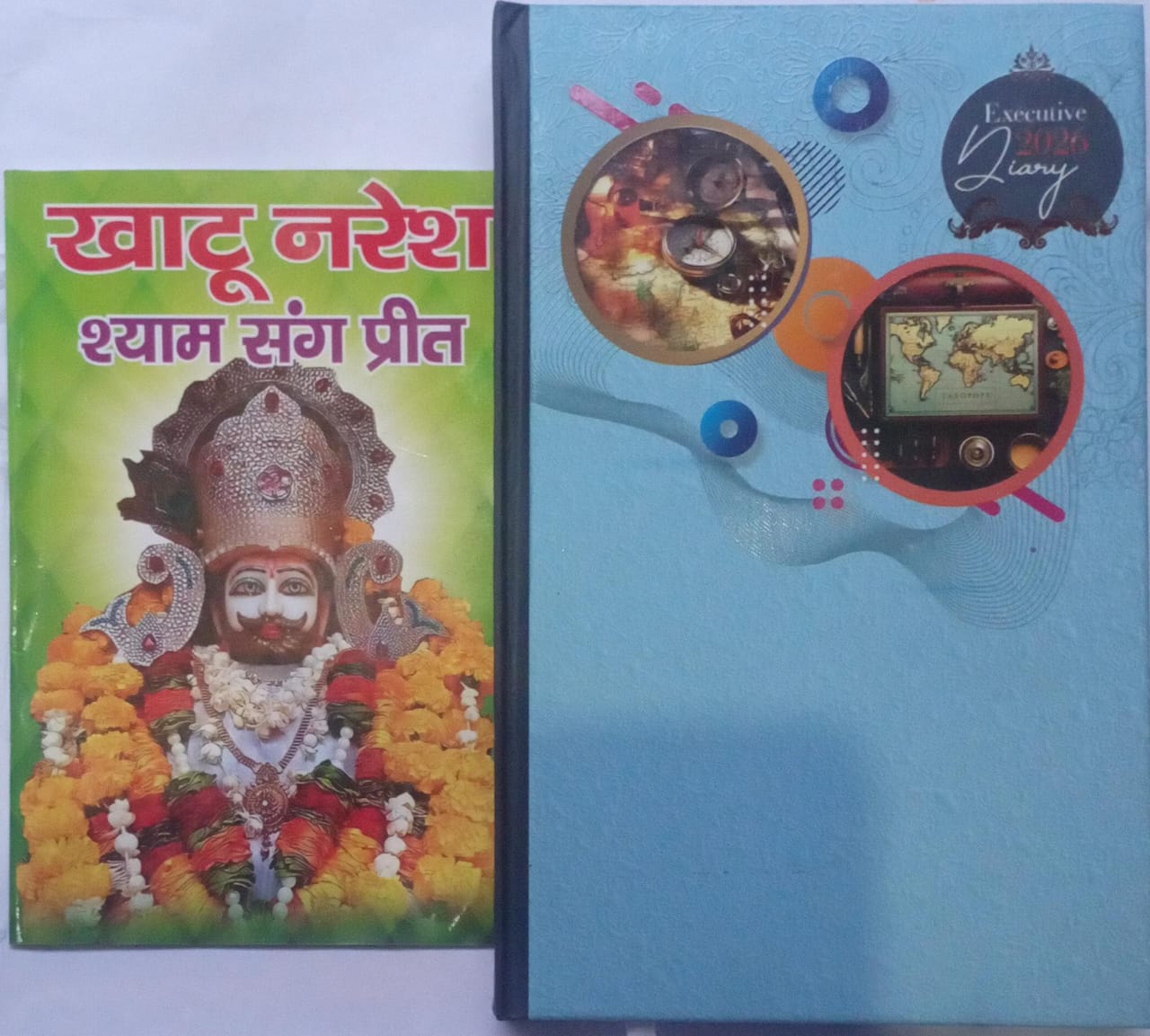 Book with colorful cover featuring a deity and a blue diary with decorative elements on a white background.