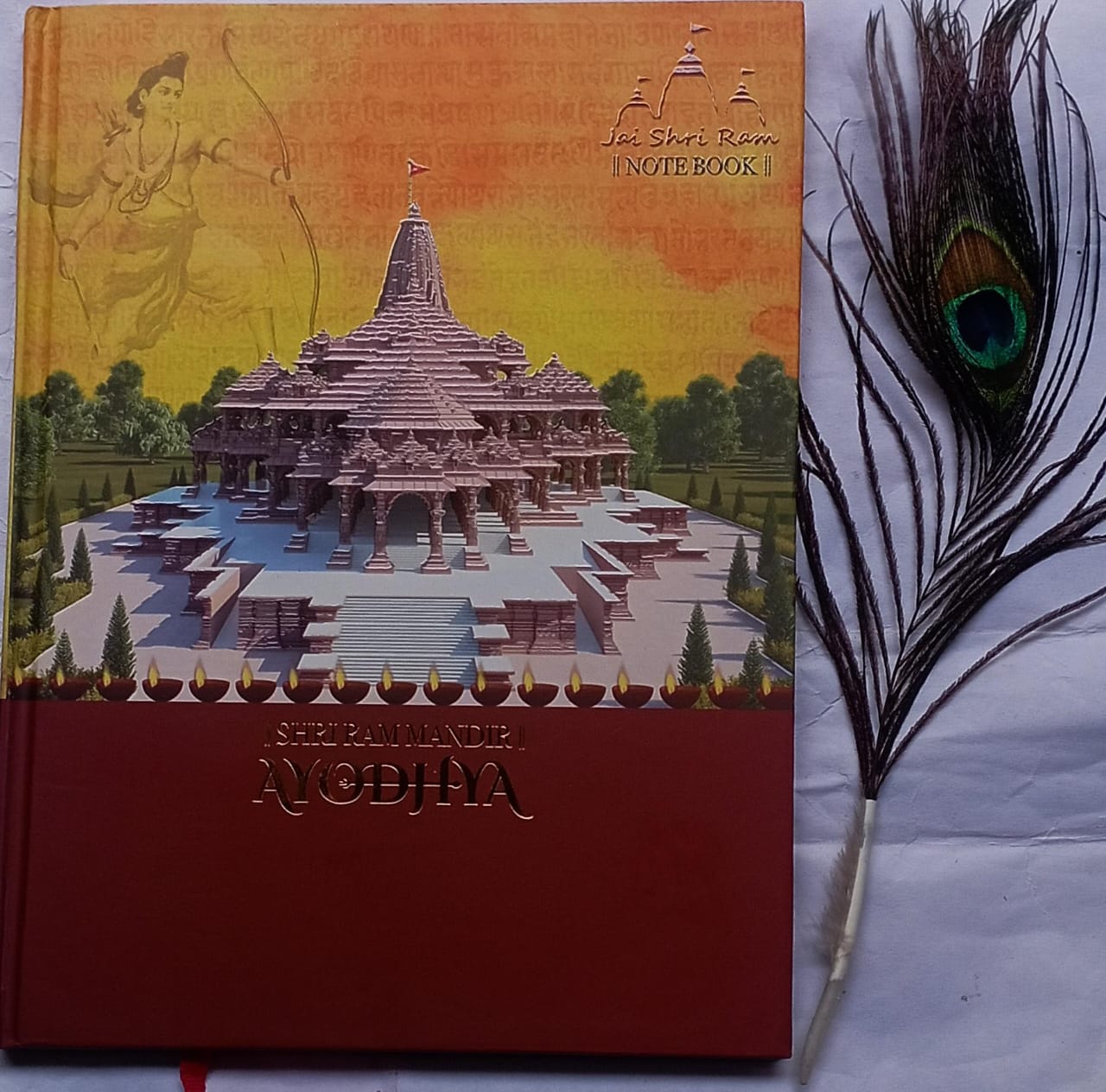 Notebook with a temple illustration on the cover, featuring a peacock feather on a white background.