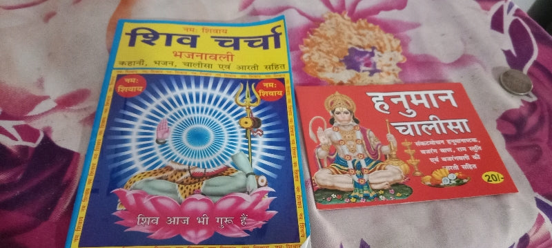 Two colorful books or packets with religious designs on a patterned fabric background