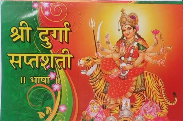 Decorative card with Goddess Durga on a tiger, surrounded by traditional elements and text.